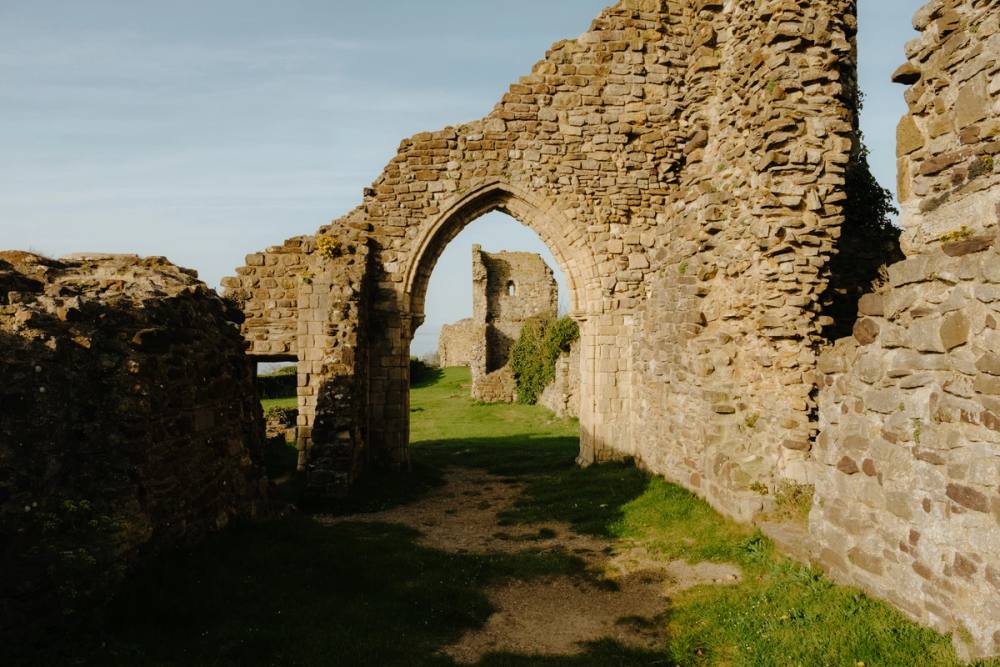 A ruined stone archway in the castle walls, with grass beneath