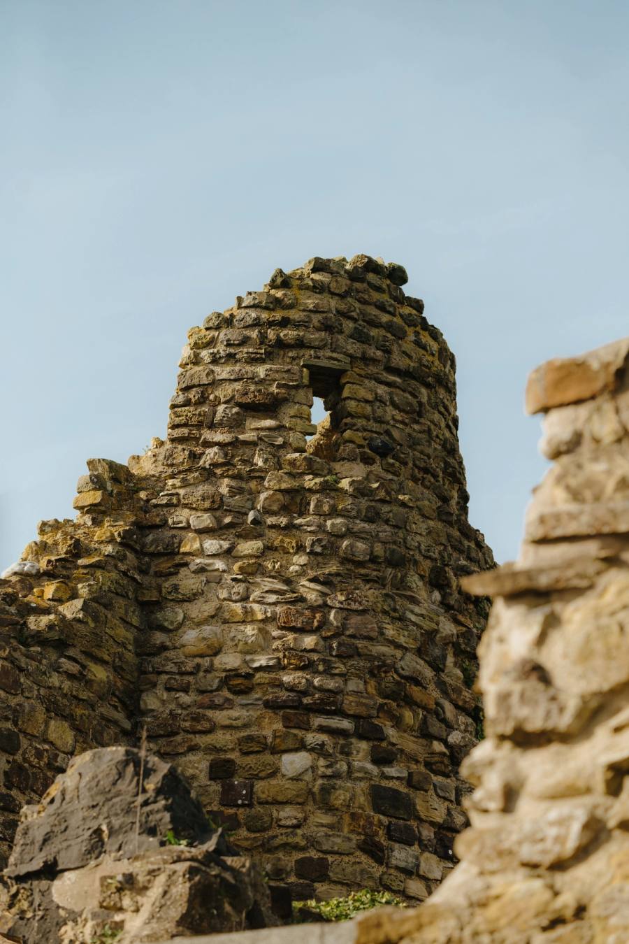 A round stone tower in the castle ruins, against a blue sky